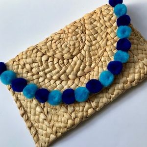 STRAW CLUTCH WITH POM POMS